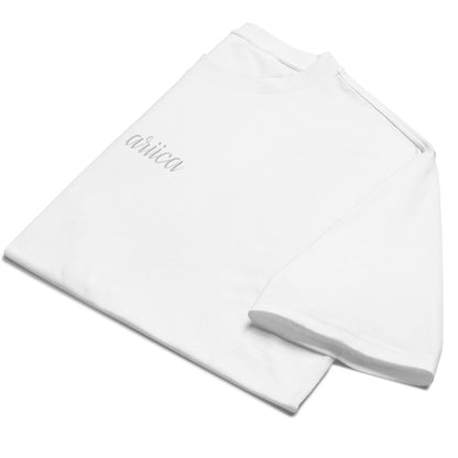 Folded Oversized White Heavyweight Tee with white Embroidery, emphasizing minimalist design and high-quality fabric